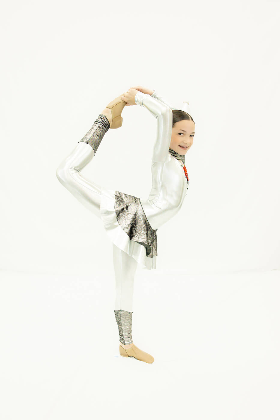 Young Tempo dancer holding a needle pose in a silver costume